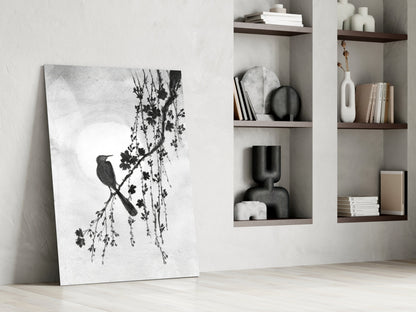 Canvas print of a bird and branch design leaning against a wall in a room with shelves.