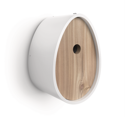 A modern wall-mounted birdhouse with a white cylindrical body and a light natural wood grain front panel featuring a central hole, shown against a plain white background.